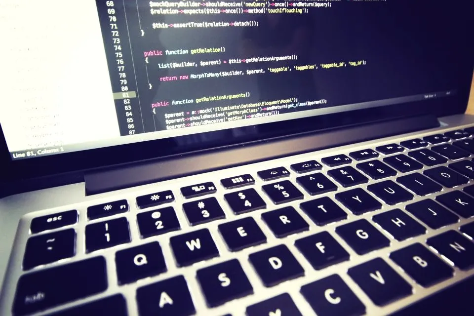 Laptop screen showing code beside a keyboard