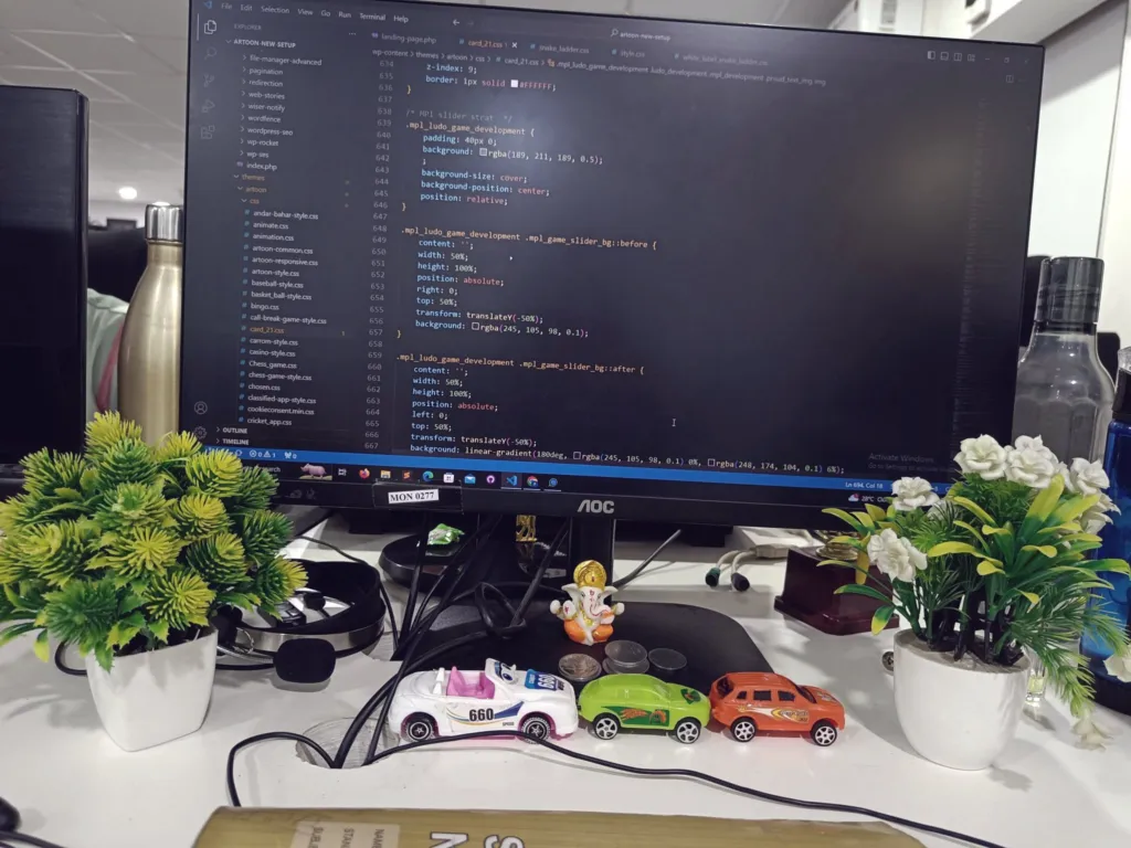 Desk with a monitor showing code and small plants