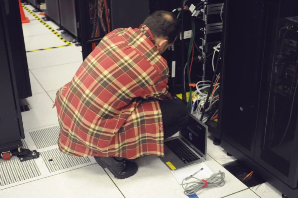Technician kneeling at a server rack with a laptop